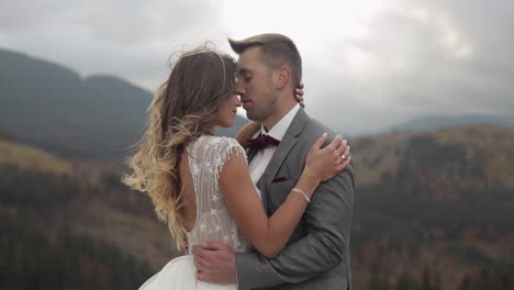 Lovely-young-newlyweds-bride-and-groom-embracing,-hugging-on-mountain-slope,-wedding-couple-in-love