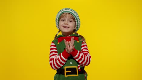 Kid-girl-Christmas-elf-Santa-helper-steepls-fingers-waiting-for-gift-box.-Child-in-New-Year-holidays