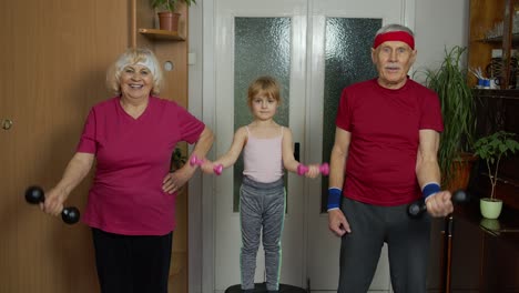 Granddaughter-and-mature-grandparents-in-sportswear-making-sports-jogging-workout-exercises-at-home