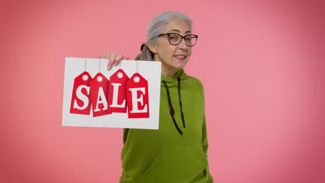 Elderly-granny-woman-showing-Sale-inscription-banner-text,-advertising-discounts-low-holidays-prices