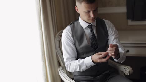 Man-in-suit-put-on-wrist-watch.-Groom-dresses.-Young-male-businessman-is-waiting-for-a-meeting