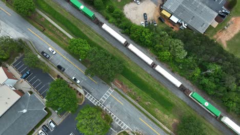 Toma-Aérea-De-Un-Tren-De-Carga-Con-Drones-En-Una-Zona-Pintoresca-De-Una-Ciudad-Estadounidense-Durante-Un-Día-Nublado