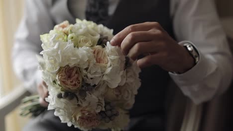 Groom-with-wedding-bouquet-in-his-hands-at-home-preparing-to-go-to-bride,-close-up-slow-motion