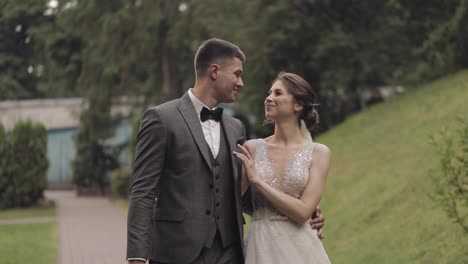 Lovely-newlyweds-caucasian-bride-groom-walking-in-park,-holding-hands,-wedding-couple-family