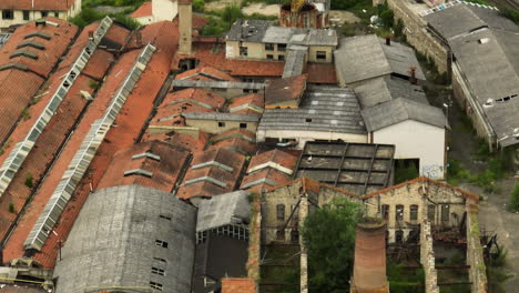 Una-Fábrica-De-Cerámica-Abandonada-Con-Techos-Rojos-En-Italia,-Rodeada-De-Vegetación,-Vista-Aérea