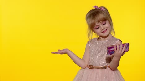 Child-girl-holding-smartphone.-Kid-pointing-at-something-with-hands,-showing,-offering-a-product