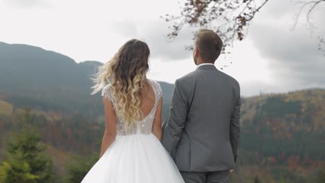 Lovely-caucasian-wedding-couple-newlyweds-family-bride-groom-stay-together-on-mountain-slope-hill