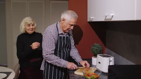 Pareja-Madura-Enamorada-Preparando-La-Cena.-Anciana-Abrazando-Desde-Atrás-Marido-Cocinando-Comida-En-La-Cocina