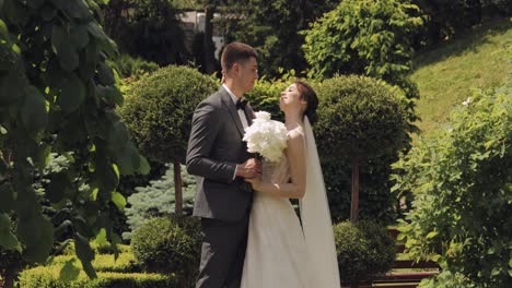 Newlyweds,-caucasian-groom-with-bride-walking,-embracing,-hugs-making-a-kiss-in-park,-wedding-couple