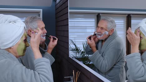 Senior-grandmother-applying-facial-mask-and-grandfather-shaving-with-manual-razor-blade-at-bathroom