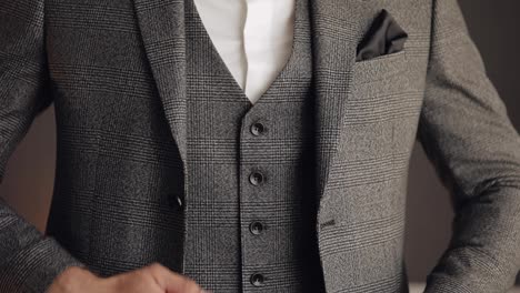 Buttoning-jacket-with-hands-close-up,-man-in-suit-fastens-buttons-on-his-jacket-preparing-to-go-out