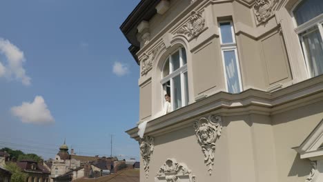 Bride-in-boudoir-dress-sitting-on-window-sill-wedding-morning-preparations-woman-in-night-gown,-veil