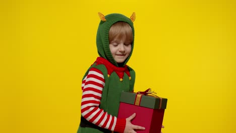 Kid-girl-Christmas-elf-Santa-helper-giving-present-gift-box-to-camera.-Happy-New-Year-holidays