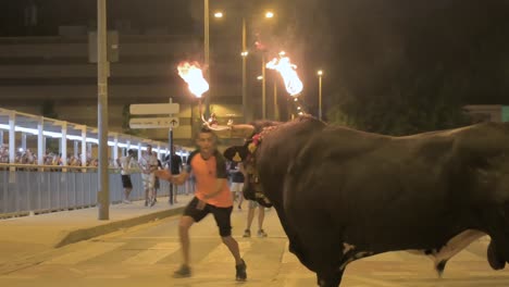 Close-up-of-a-large-bull-with-fireballs-in-its-horns-at-a-running-of-the-bulls-with-spectators-at-a-toro-embolado-event-in-Sagunto