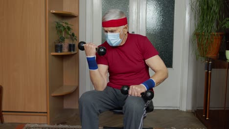 Senior-elderly-caucasian-man-making-weight-lifting-dumbbells-exercising-at-home-during-coronavirus