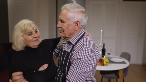 Senior-couple-in-love-have-romantic-evening,-dancing-together-in-kitchen,-celebrating-anniversary