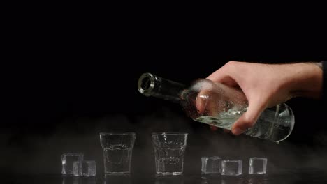 Two-hands-with-glasses-of-vodka-making-cheers,-raising-toast-on-black-background-with-ice-cubes