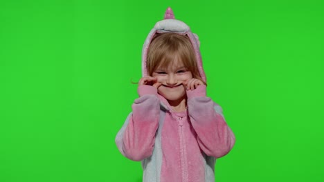 Child-girl-in-unicorn-pajamas-making-silly-funny-faces,-fooling-around,-showing-tongue-on-chroma-key