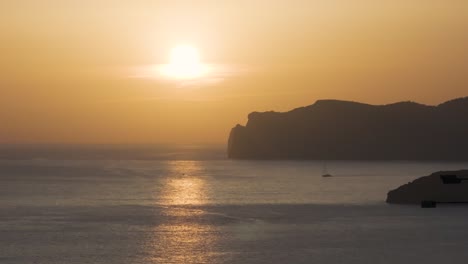 Calm-yellow-hue-sunset-scenery-with-mountain-silhouette-in-sea,-Mallorca