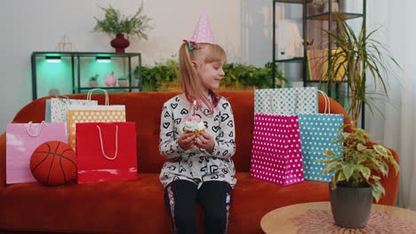 Young-little-children-girl-sitting-on-sofa-with-lots-of-gifts-celebrating-birthday-party-anniversary