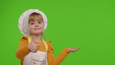 Child-girl-dressed-cook-chef-in-apron-pointing-at-right-on-blank-space-on-chroma-key-background