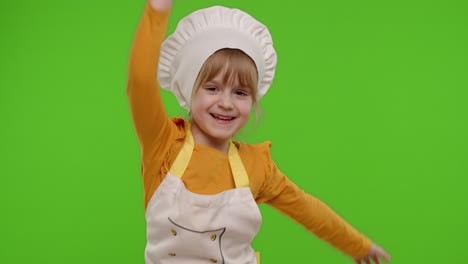 Funny-child-girl-kid-dressed-cook-chef-baker-in-apron-and-hat-dancing,-fooling-around,-making-faces