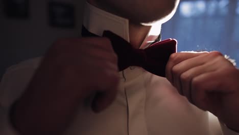 Groom-adjusts-bow-tie,-preparing-to-go-to-the-bride,-businessman-in-white-shirt,-wedding-day