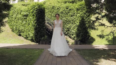 Beautiful-lovely-stylish-bride-in-white-wedding-dress-and-veil-walking-in-park-and-waiting-for-groom