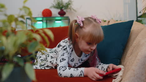 Worried-teen-child-girl-kid-enthusiastically-playing-shooter-video-online-game-on-smartphone-at-home