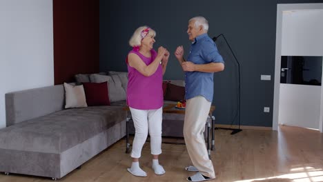 Feliz-Pareja-De-Ancianos-Bailando-Divirtiéndose-Celebrando-El-Aniversario-De-Jubilación-En-El-Salón-De-Casa