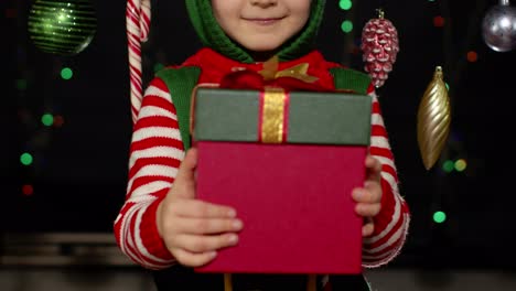 Kid-girl-in-Christmas-elf-Santa-Claus-helper-costume-getting,-receiving-surprise-gift-box,-happiness