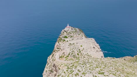 Far-aerial-view-of-Formentor-Lighthouse-tower-on-limestone-cliff,-Mallorca