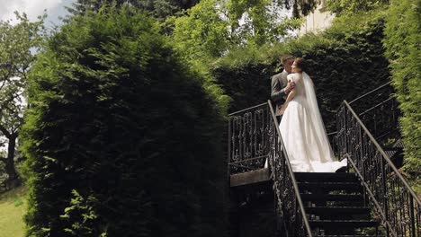 Newlyweds,-caucasian-groom-with-bride-stay-on-stairs-in-park,-wedding-couple,-man-and-woman-in-love