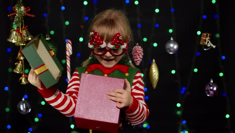 Kleines-Mädchen-Im-Weihnachtselfenkostüm-Als-Weihnachtsmannhelfer-Mit-Geschenkbox,-Blick-Hinein.-Schöne-Feiertage