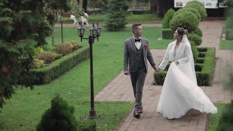 Lovely-newlyweds-caucasian-bride-groom-walking-in-park,-holding-hands,-wedding-couple-family