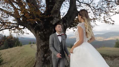 Lovely-young-newlyweds-bride-groom-embracing-on-mountain-slope,-happy-wedding-couple-family-in-love