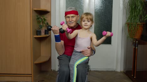 Active-grandfather-senior-man-with-child-girl-doing-fitness-weight-lifting-exercises-with-dumbbells