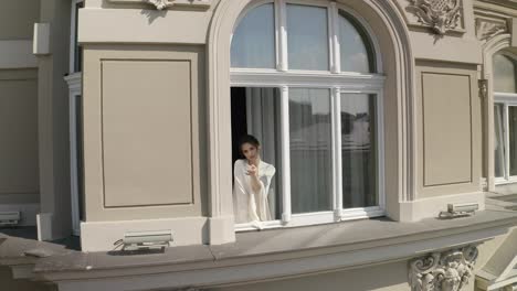 Aerial-shot-of-bride-in-boudoir-dress-stay-near-window-wedding-morning-of-woman-in-night-gown,-veil