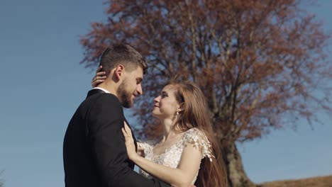 Newlyweds.-Caucasian-groom-with-bride-near-beautiful-autumn-tree.-Wedding-couple