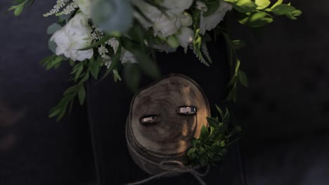 Beautiful-wedding-rings-lie-on-wooden-stand-with-wedding-bride's-bouquet