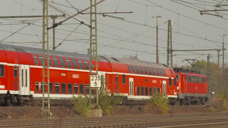 Roter-Regionalzug-Der-Deutschen-Bahn-Fährt-Auf-Gleisen,-Umgeben-Von-Herbstlaub