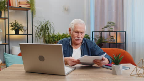 Stressed-senior-man-looking-at-unpaid-bank-debt-loan-doing-paperwork-planning-budget-throws-bills