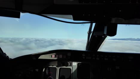 Immersive-pilot-POV-inside-a-jet-cockpit-arriving-to-Funchal-Madeira-airport-with-the-peaks-of-the-mountains-over-a-sea-of-clouds