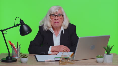 Senior-mature-older-office-businesswoman-working-on-laptop-computer-making-funny-face-fooling-around