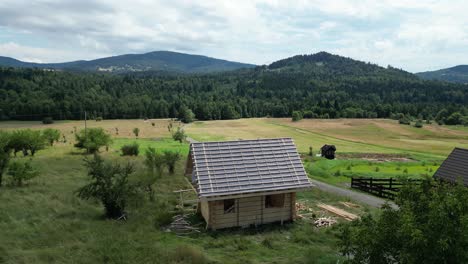 Wooden-house-under-construction,-made-of-logs-and-located-in-beautiful-landscape-during-a-beautiful-summer-day