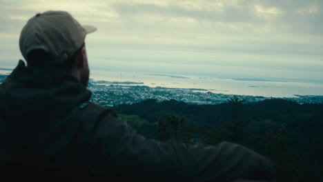 Over-the-shoulder-shot-of-a-man-sitting-on-a-bench-and-looking-out-at-the-views