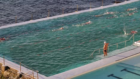 Erhöhte-Ansicht-Von-Menschen,-Die-Bei-Sonnenaufgang-Im-Pool-Bei-Bondi-Icebergs-Schwimmen