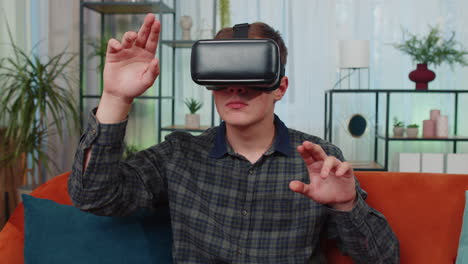 Un-Joven-Usa-Gafas-De-Realidad-Virtual-En-Casa,-Disfrutando-Del-Concepto-De-Vídeo-Moviendo-Las-Manos-En-El-Aire