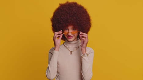 Alegre-Y-Encantadora-Niña-Adolescente-Sonriendo,-Mirando-A-La-Cámara-En-Un-Estudio-Con-Fondo-Amarillo