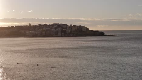 Wide-view-of-North-Bondi-from-Bondi-Beach-with-surfers-and-swimmers-in-the-ocean-at-sunrise